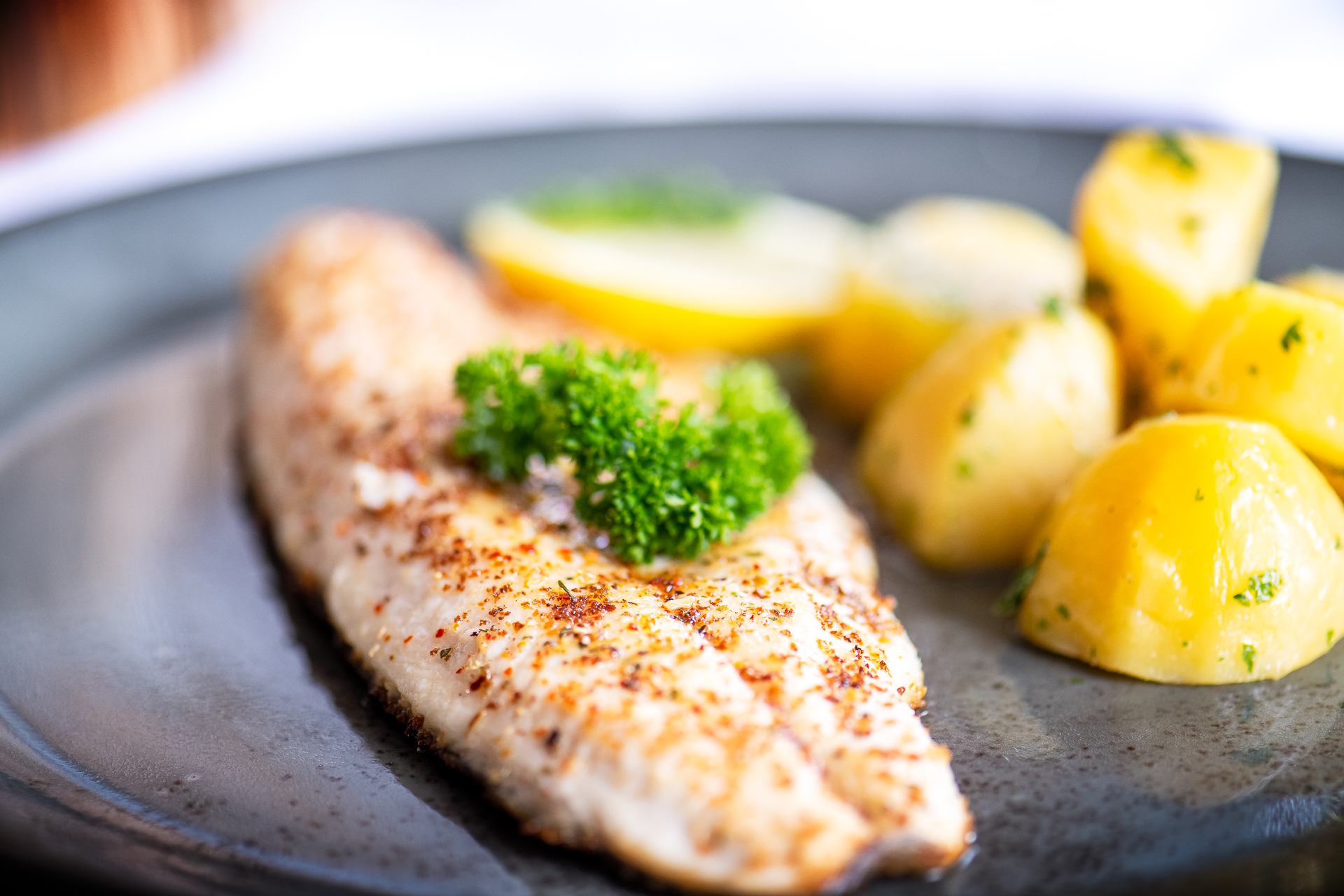Pan-fried fish fillet with parsley potatoes and a lemon wedge