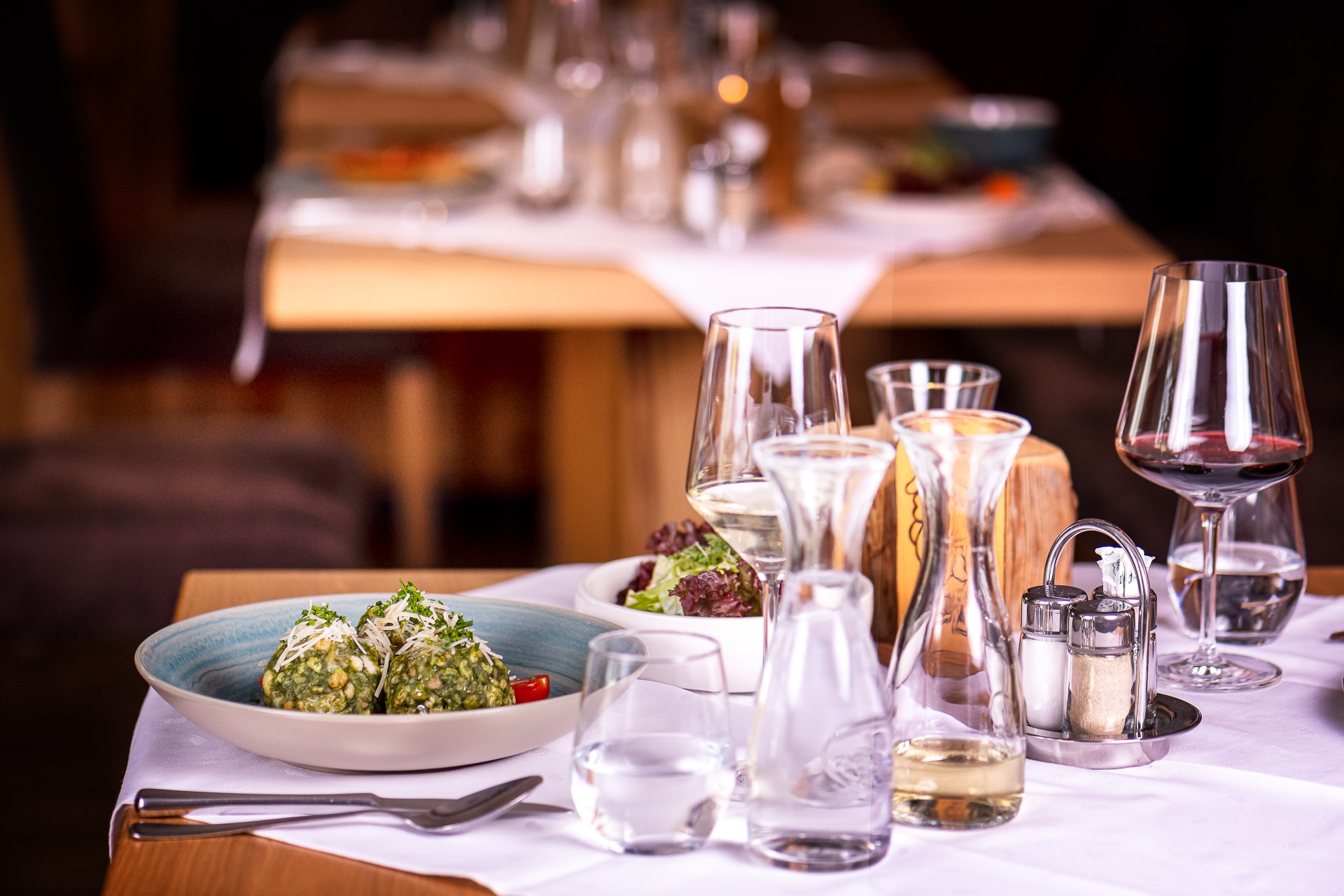 Festlich gedeckter Tisch mit Spinatknödel und Wein
